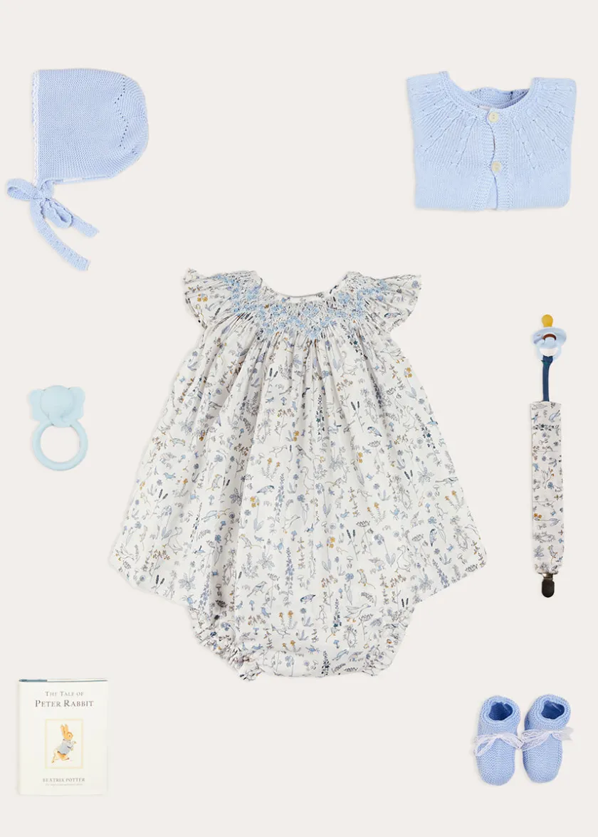 Lookbooks | Pepa London Ellis Sleeveless Dress with Bloomer and Bows in Blue Made with Liberty Fabric (1-12m) | Openwork Detail Baby Cardigan in Blue (1-12mths) | Lace Detail Knitted Bonnet in Blue (1-6mths) | Lace Detail Knitted Booties in Blue | Ellis Dummy Clip in Blue Made with Liberty Fabric | BIBS Dummy in Blue