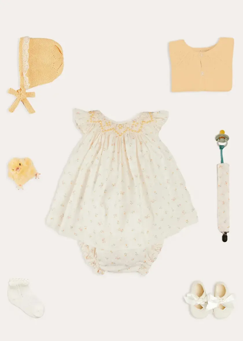 Lookbooks | Pepa London Esme Floral Hand Smocked Sleeveless Dress With Bloomers in White (1-12mths) | Openwork Detail Cotton Baby Cardigan in Tangerine (1-12mths) | Lace Detail Knitted Bonnet in Tangerine (1-12mths) | Celebration Ribbon Detail Mary Jane Pram Shoes in Beige (17-20EU) | Esme Floral Dummy Clip in White | Openwork short socks White (0mths-8yrs) | Chick Toy in Yellow
